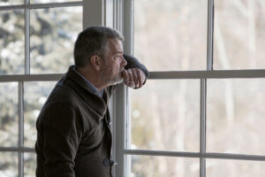 Man Looking Out the Window Depressed From a Physical Dependence to Alcohol