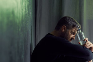 man holding a bottle and thinking about alcohol abuse facts
