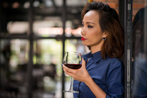 woman thinking about the alcoholism statistics, holding a glass of wine.