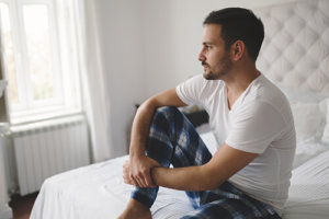 Man on bed exhibiting heroin addiction signs